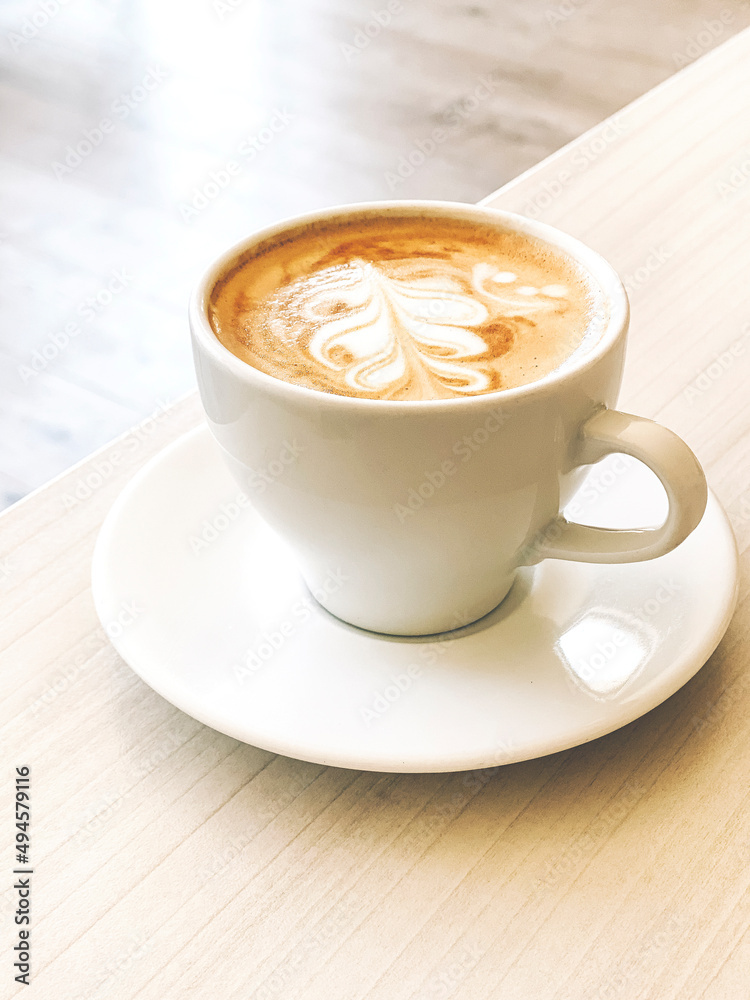 High angel view of fresh cappuccino coffee in white ceramic cup on table. High angel view of fresh cappuccino coffee in white ceramic cup on table.