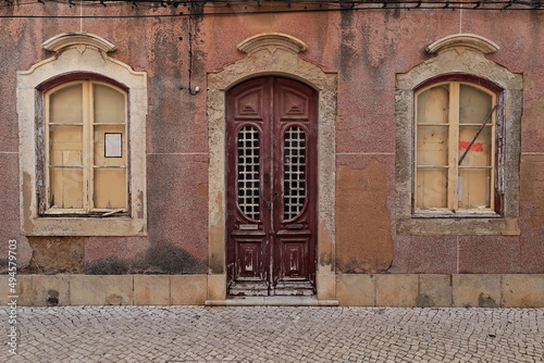 Paint faded windows-wooden door-façade of long abandoned Neoclassical townhouse. Faro-Portugal-159