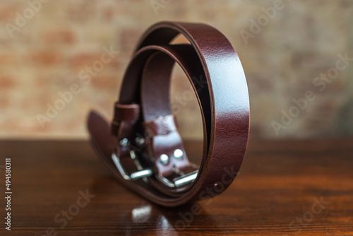 Men's leather trouser belt in the background of aged wood.