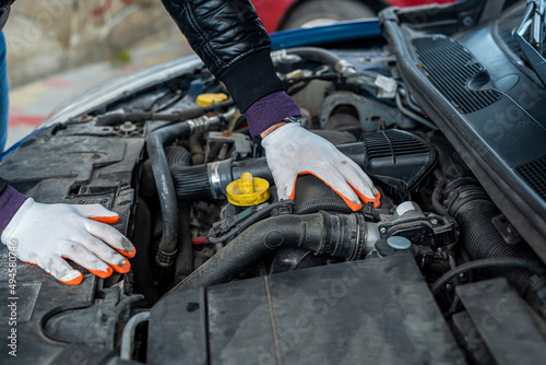a professional good mechanic in special gloves diagnoses the car. © RomanR
