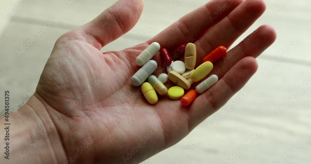 Many tablets and vitamins in a male hand, POV, first-person view Many tablets and vitamins in a male hand, POV, first-person view
