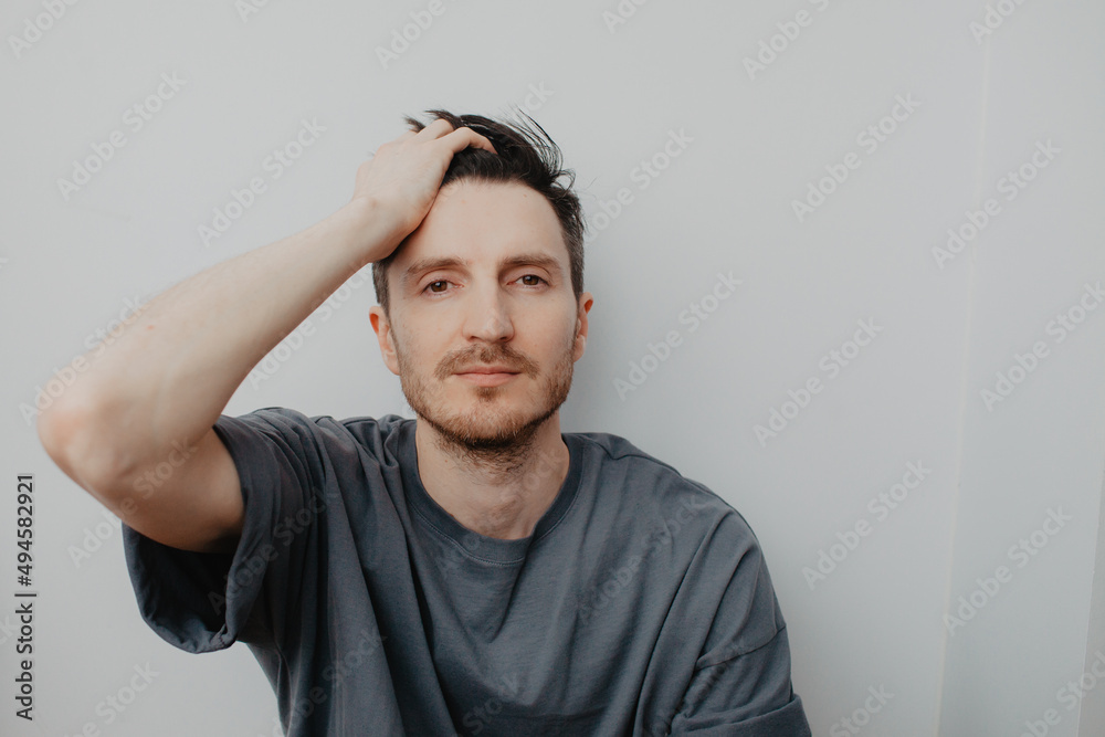 Handsome young man over grey wall with serious expression on face. Simple natural looking at camera. Handsome young man over grey wall with serious expression on face. Simple natural looking at camera.