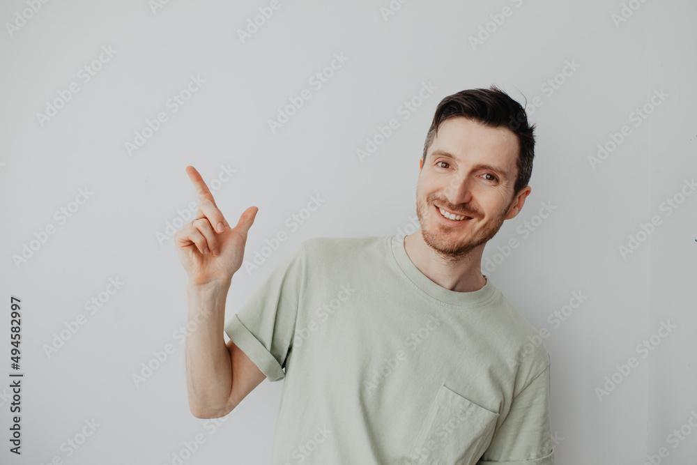 Handsome young man over grey wall with happy face pointing his finger Handsome young man over grey wall with happy face pointing his finger