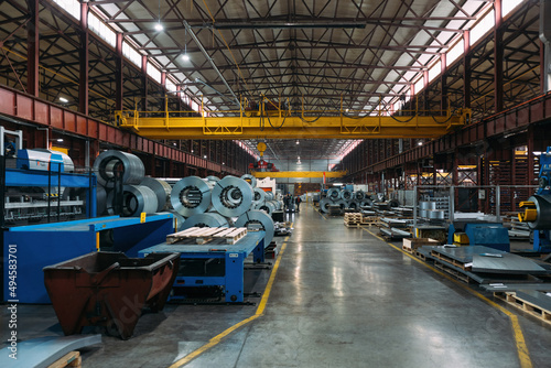 Metalworking factory production line. Rolls of steel and metal profiled parts in workshop