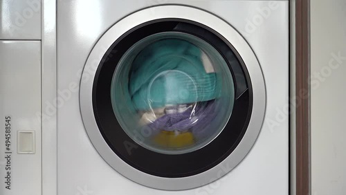 Colorful laundry inside a front loader washing machine spinning counter clockwise