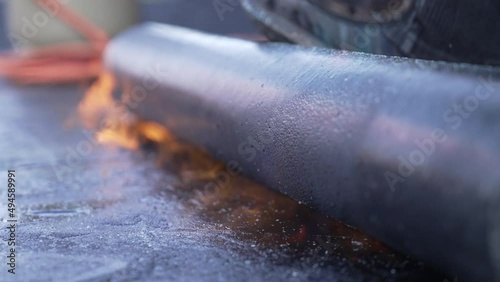 Roofer is welding the roofing felt with fire on a flat roof