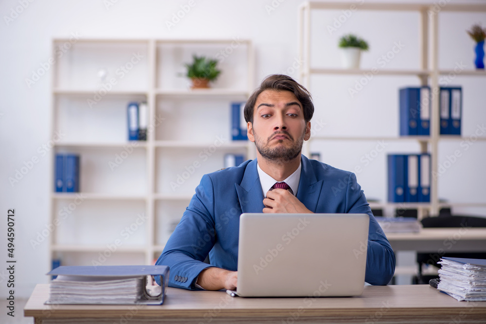 Young male employee and too much work in the office Young male employee and too much work in the office