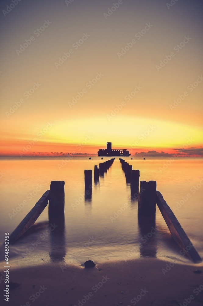 Obraz premium Beautiful sunrise over the Polish sea. The building of the old torpedo house in the Baltic Sea in Gdynia. Long exposure photo.