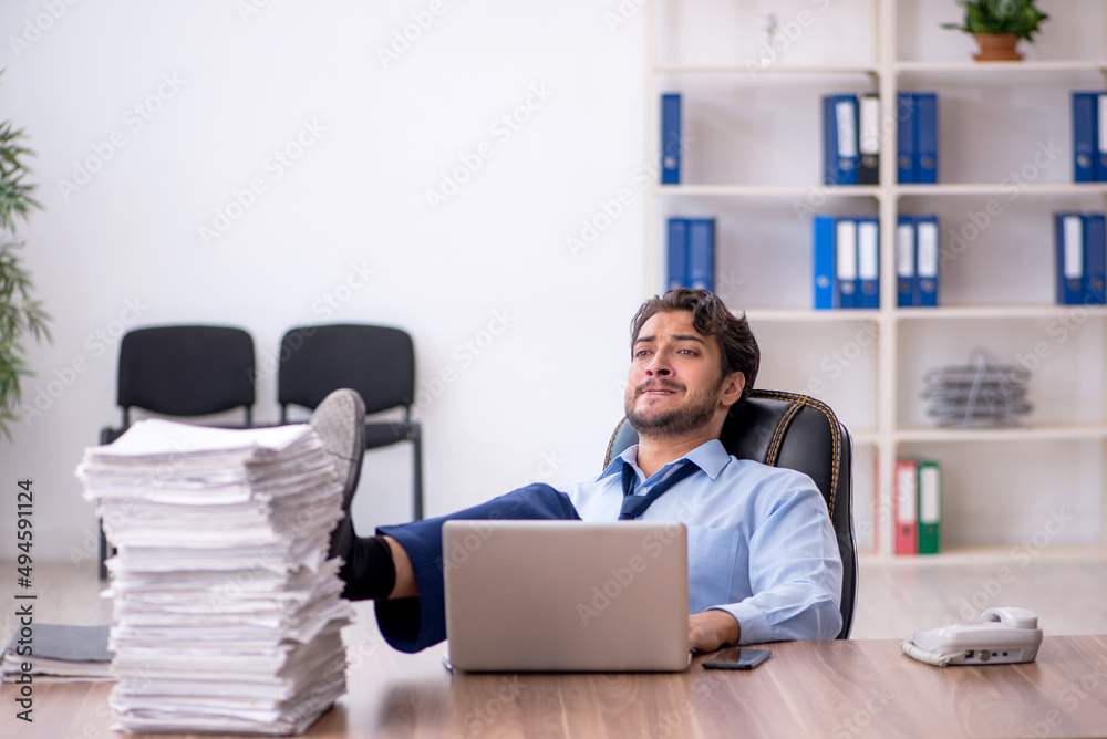 Young male employee and too much work in the office Young male employee and too much work in the office