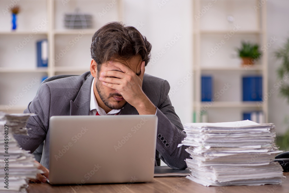 Young male employee unhappy with excessive work in the office