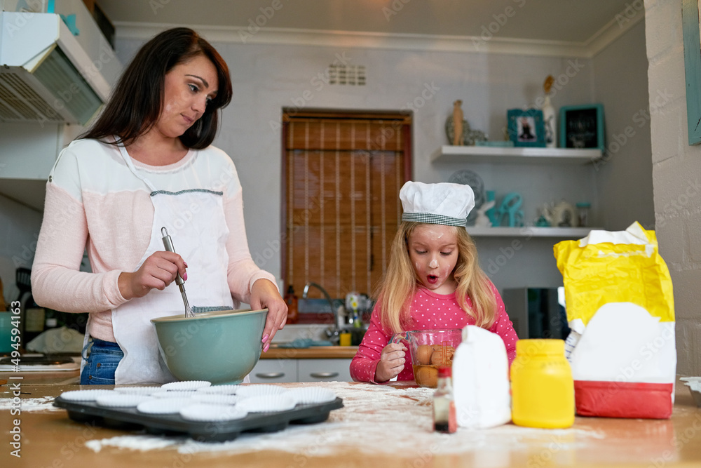 Teaching her daughter the baskics of baking. Cropped shot of a little girl baking in the kitchen with her mom. Teaching her daughter the baskics of baking. Cropped shot of a little girl baking in the kitchen with her mom.
