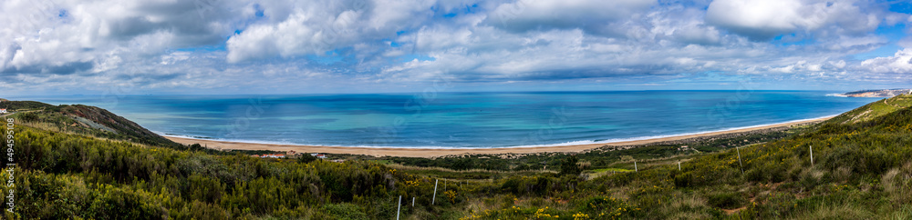 Panoramic view of the Beautiful beach of Salgados with the village of Nazare in the background, Portugal. Beautiful beach with turquoise waters in a cloudy day Panoramic view of the Beautiful beach of Salgados with the village of Nazare in the background, Portugal. Beautiful beach with turquoise waters in a cloudy day