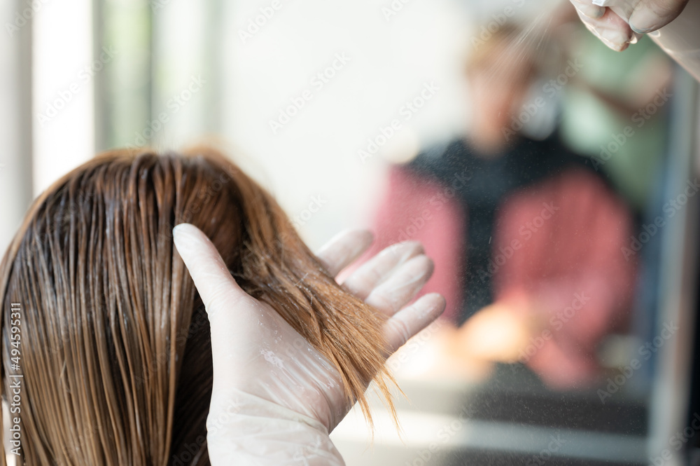 Fototapeta premium woman client person having a process to making treatment a hair with hairdresser in beauty salon