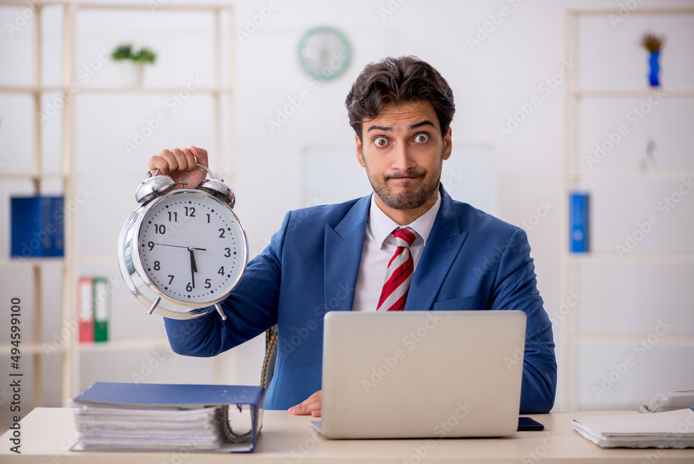 Young male employee in time management concept Young male employee in time management concept