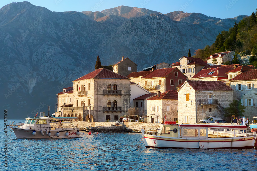 Breathtaking panoramic sunset view of the ancient city of Perast, Montenegro. Old medieval little town with red roofs and with majestic mountains on background of Adriatic sea.