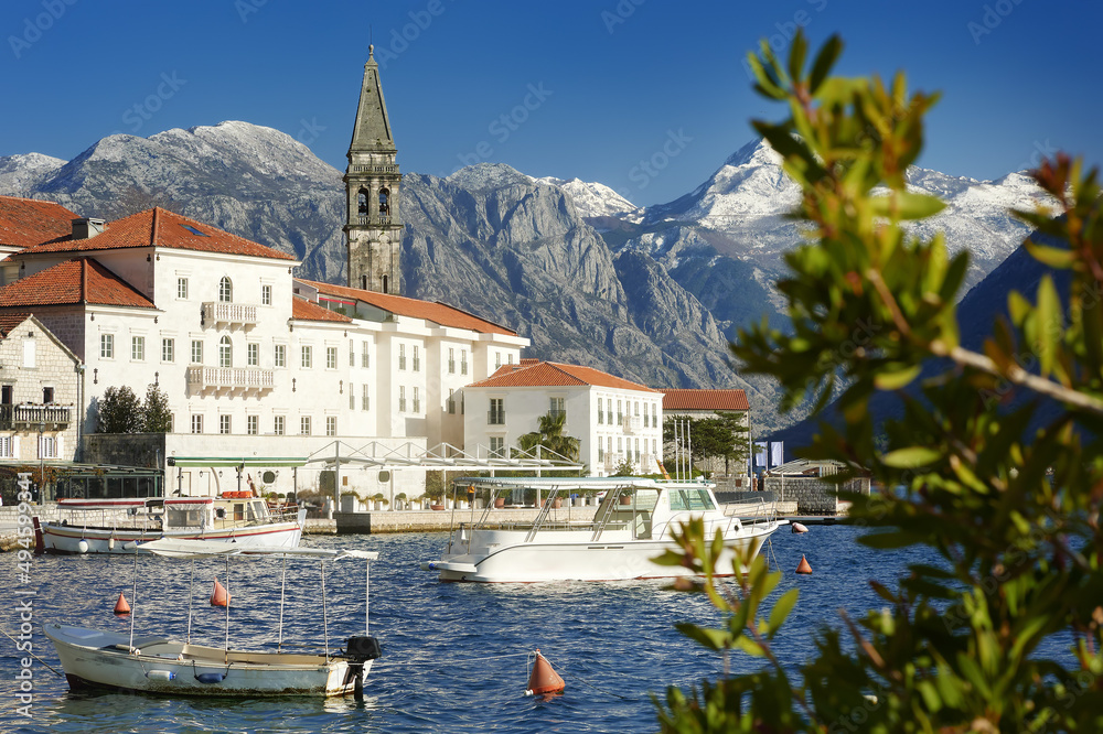 Picturesque view of ancient city of Perast, Montenegro. Boy in old medieval little town with red roofs and majestic mountains on background. Kotor bay.