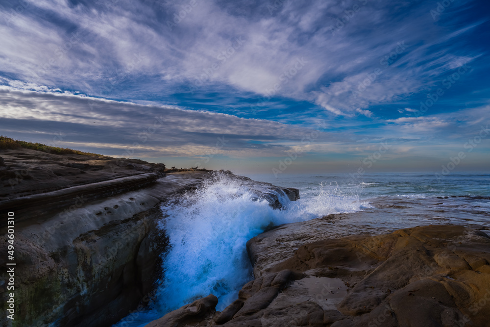 2022-03-23 WAVES CRASHING INBETWEEN THE ROCKY SHORELINE IN LA JOLLA CALIFORNIA WITH A CLOUDY SKY