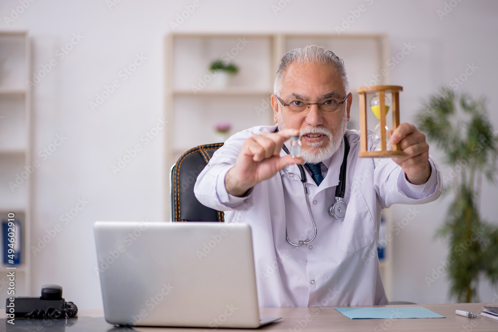 Old male doctor in time management concept