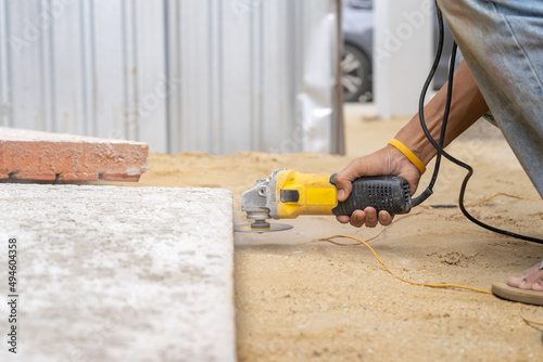 Close up worker holds Hand-Hold Sawing Machine and cuts brick foam plate board for wall installation.