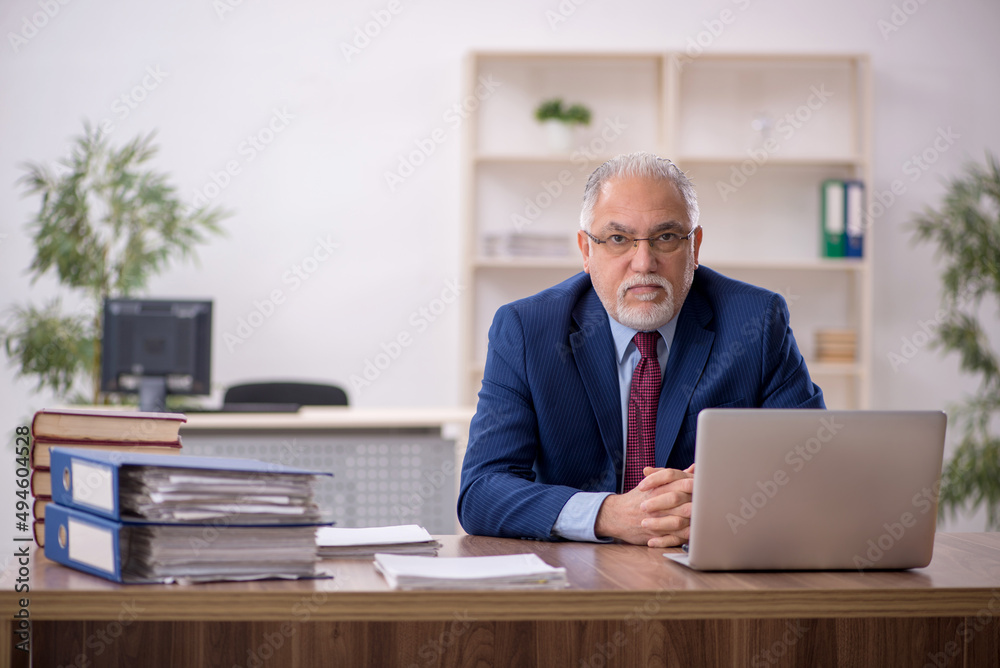Old male employee working at workplace Old male employee working at workplace
