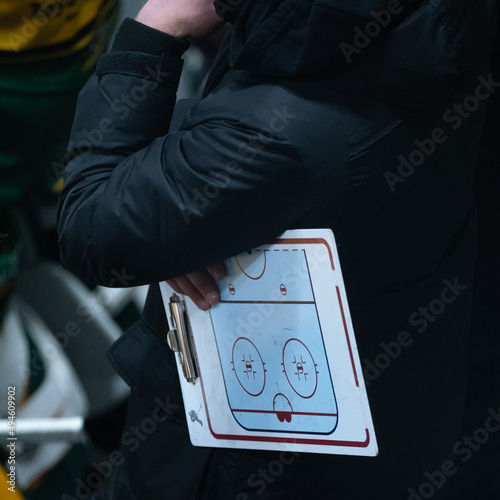 Ice hockey coach holding a flip chart while watcing the game