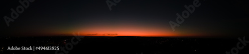 Aerial shot of final light of a distant sunsets afterglow with street lights below