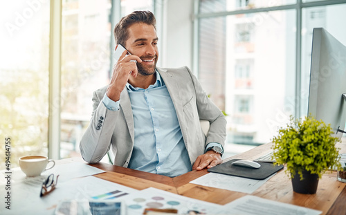 Thats just the news I was hoping to hear. Shot of a handsome young businessman talking on a cellphone in an office. photo