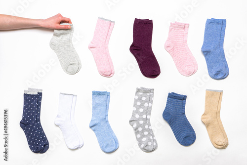 Female hand holding socks among women's cotton socks set on white background. Fashionable socks store. Socks shopping, sale, merchandise, advertisement concept