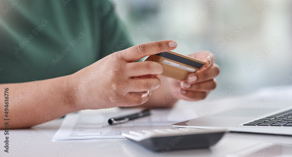 Banking just gets easier by the day. Shot of an unrecognisable woman using a laptop and credit card at her desk. Banking just gets easier by the day. Shot of an unrecognisable woman using a laptop and credit card at her desk.