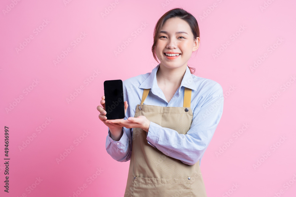 Young Asian waitress standing on pink background Young Asian waitress standing on pink background