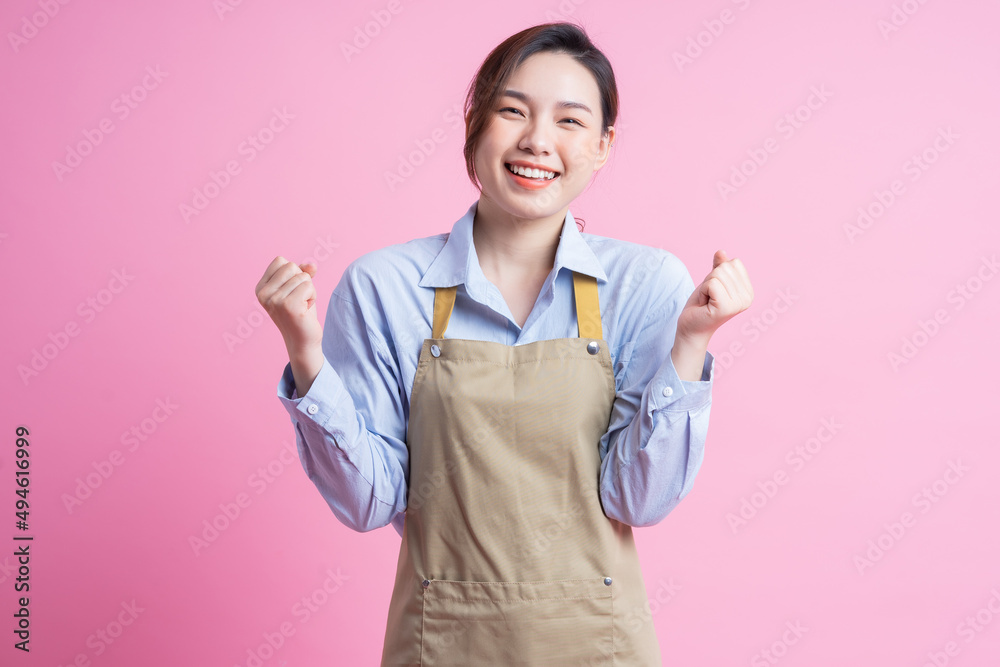Young Asian waitress standing on pink background Young Asian waitress standing on pink background