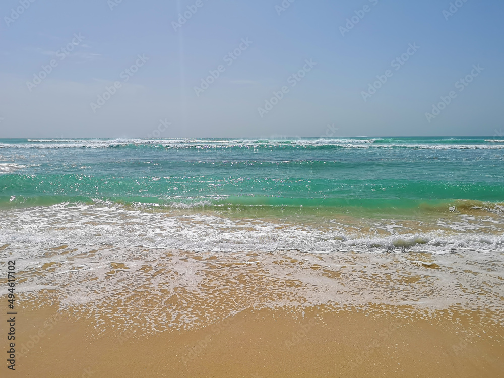 Clear blue ocean water in Africa. White foam on the waves, turquoise transparent surface, sunny day. Selective focus on the details, blurred background.