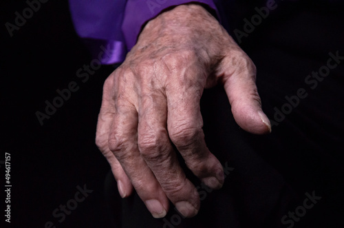 Hands of an elderly woman on a black background, the concept of old age. 