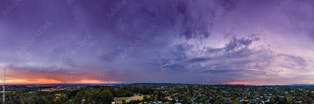 Stormy rain clouds in the afterglow of sunset glowing purple, blue and orange aerial panoramic Stormy rain clouds in the afterglow of sunset glowing purple, blue and orange aerial panoramic