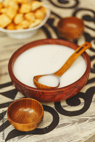 Koumiss milk drink in a wooden bowl with an ornament in the national Kazakh style on the table. Central Asian traditional drink on the festive table Nauryz. photo