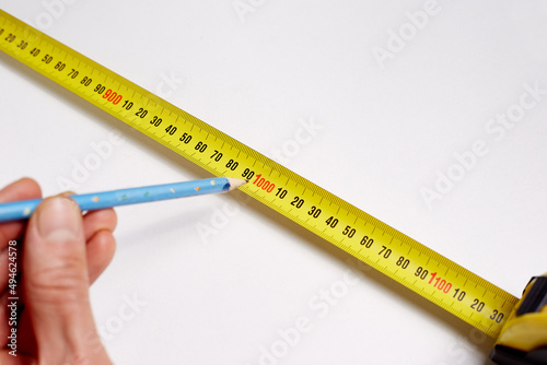 On a white background in the hand of a simple pencil and measuring meter, construction repair concept