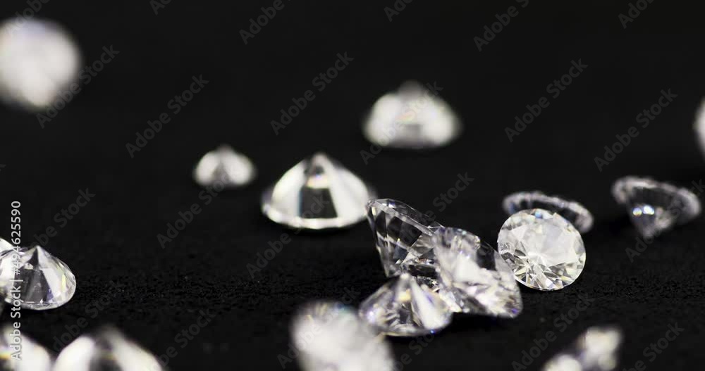 Slow-motion shot of real shining brilliant-cut diamonds falling down the black the sorting table in a jewelry store Slow-motion shot of real shining brilliant-cut diamonds falling down the black the sorting table in a jewelry store