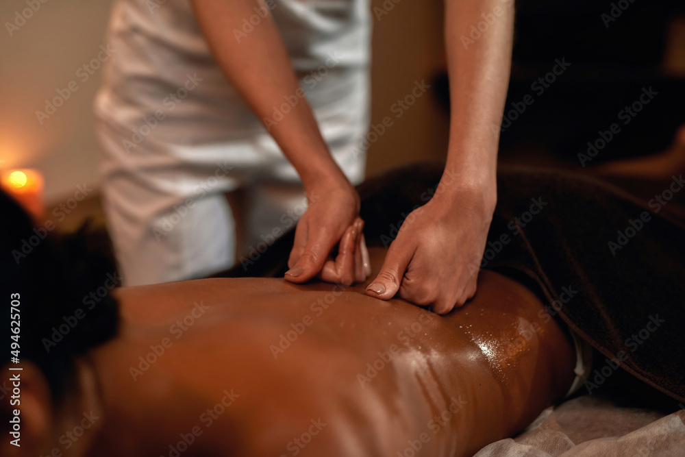 Masseur doing massage of black woman in spa salon