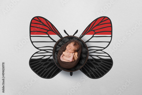 Tiny baby portrait with wings in color of national flag. Newborn photography concept. Yemen