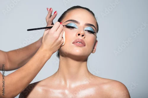 Obraz Sexy makeup for party. Makeup artist applies eye shadow. Hand of visagiste, painting cosmetics of young beauty model girl. Beautiful sensual young woman with sexy make up, close-up portrait.