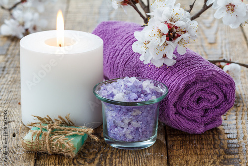 Soap, sea salt with towel and burning candle with flowering branch