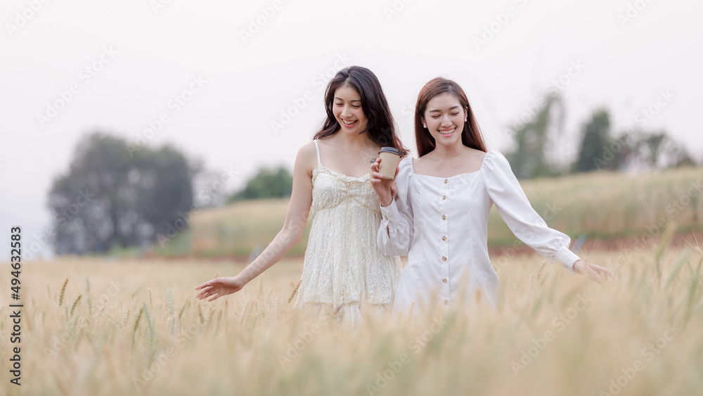 two young asian women friends take walking relax and drink coffee cup in her hand at barley field agriculture demonstration plot chiangmai province two young asian women friends take walking relax and drink coffee cup in her hand at barley field agriculture demonstration plot chiangmai province