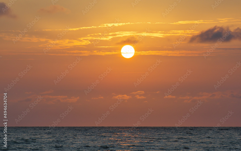  Bright beautiful sunset at the calm sea. Solar disk over water.