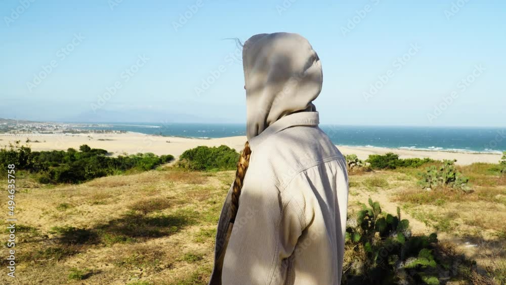 Close up shot of Woman wearing hoodie during windy day and watching beautiful sand dunes and Ocean of Vietnam