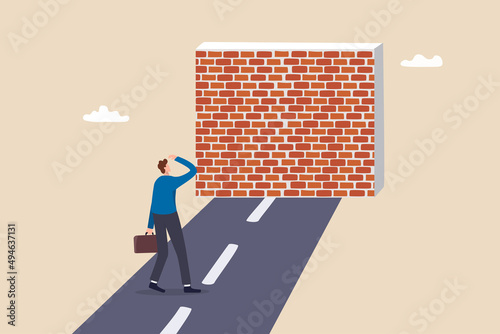 Business barrier, obstacle or difficulty, road block or career struggle, trouble or problem to be solved, prohibited or dead end concept, confused businessman walk on the road to brick wall barrier. photo