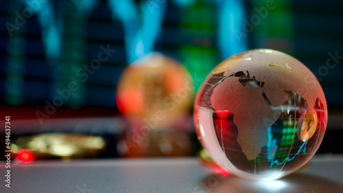 Gold coins and crystal earth globe with bitcoin symbol collaged, on computer, in front of graphic image. Focus on crystal earth globe.