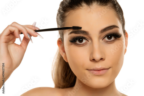 Young woman correcting eyebrow shape with brush 