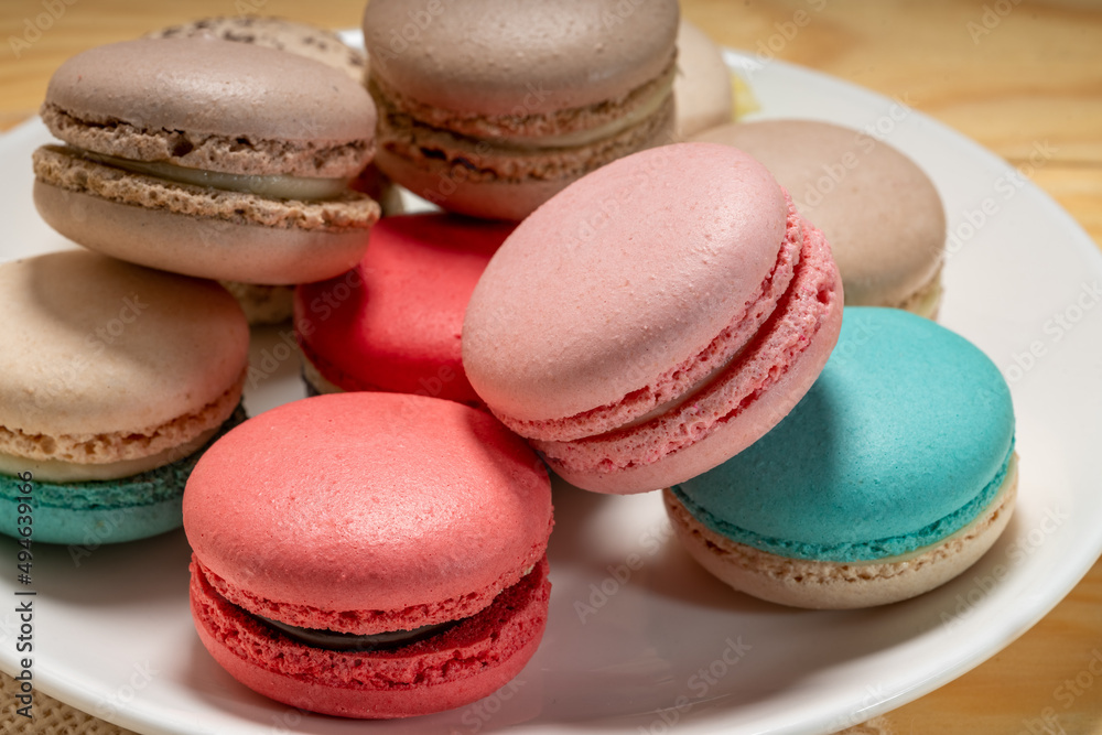Obraz premium Close up macaron dessert pastel tones on white plate , Sweet and colorful french macaroons on wooden background, Dessert.