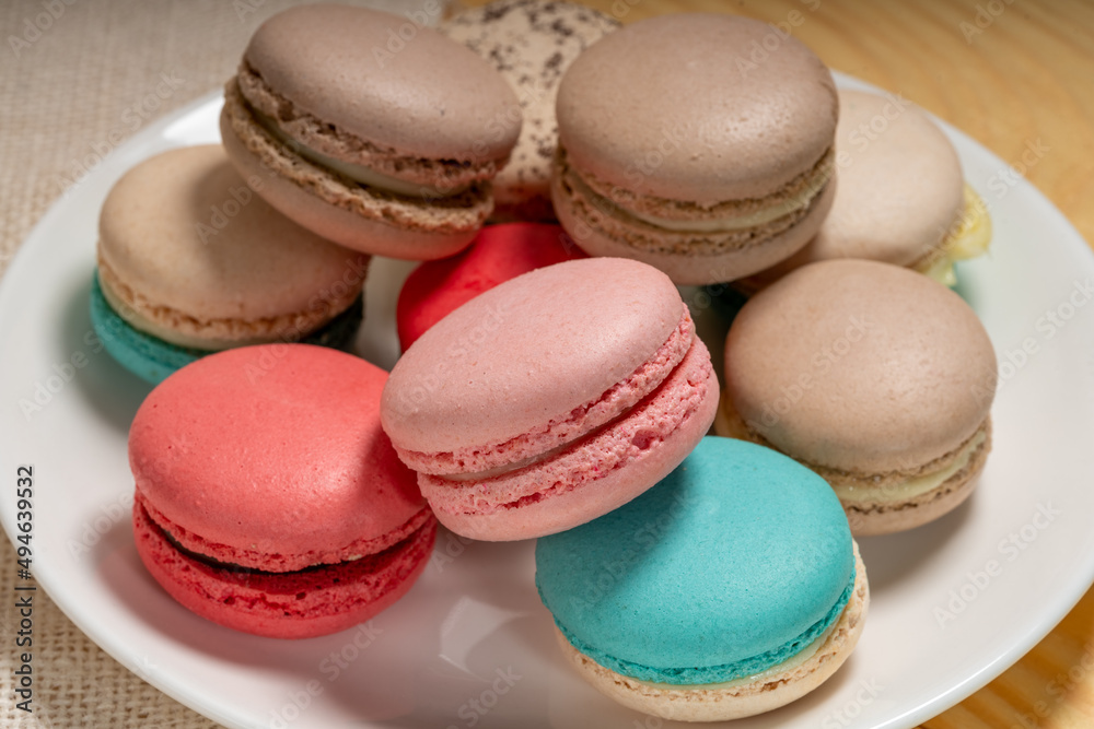 Close up macaron dessert pastel tones on white plate , Sweet and colorful french macaroons on wooden background, Dessert. Close up macaron dessert pastel tones on white plate , Sweet and colorful french macaroons on wooden background, Dessert.
