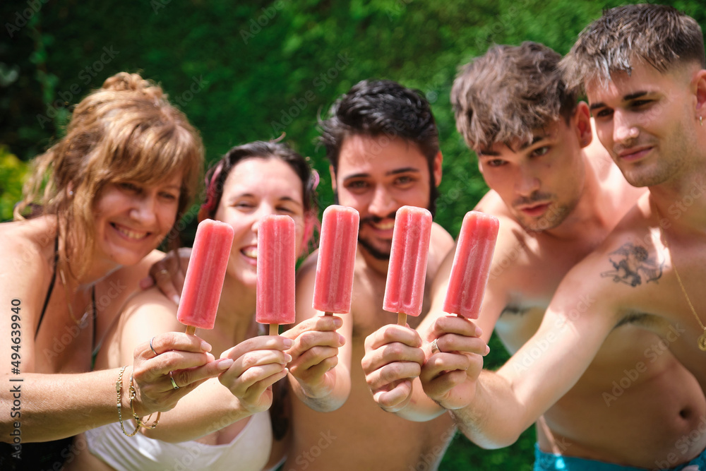 Group of people showing strawberry popsicles to the camera and having fun at the swimming pool. Group of people showing strawberry popsicles to the camera and having fun at the swimming pool.